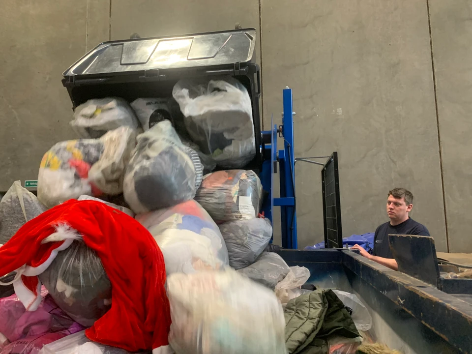 Kaspar Nedergaard tømmer entekstilaffaldscontainer ned i en stor omlastercontainer.